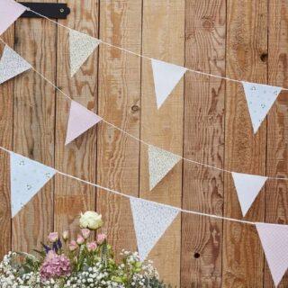 Houten muur met daarvoor een vlaggenlijn met bloemetjes erop en bloemen onderin