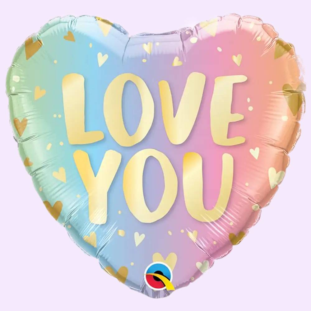 Hartvormige folieballon regenboogkleur met de tekst 'love you' op een lichtroze achtergrond