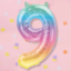 Pastelkleurige ballon nummer 9 in de kleuren van de regenboog op een roze achtergrond met confetti
