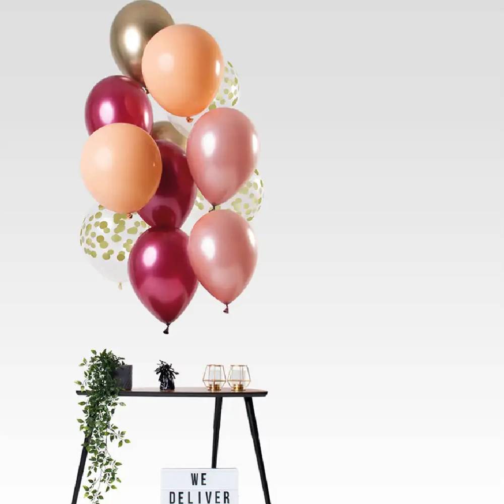 Ballonnenbundel met verschillende roze tinten boven een tafeltje met plant