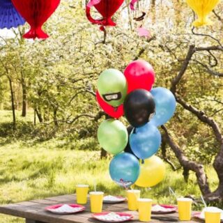 Ballonnen set met superhelden boven een tafel met gele bekertjes en rode bordjes