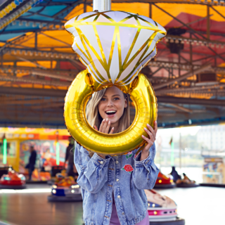 vrouw op een kermis met een folieballon in de vorm van een ring