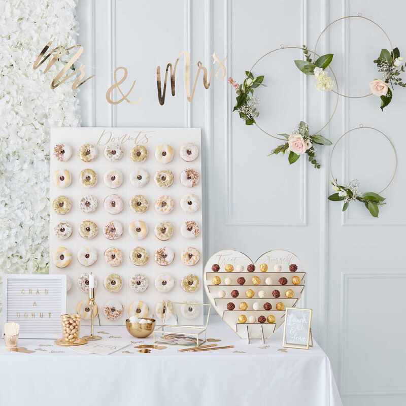 Gedekte tafel voor een bruiloft met donut wall en chocolaatjes standaard