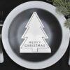 Wit servet in de vorm van een kerstboom op een zwart bord