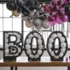 Ballonnen standaard in de vorm van de letters BOO gevuld met witte ballonnen bedrukt met spinnenwebben op tafel