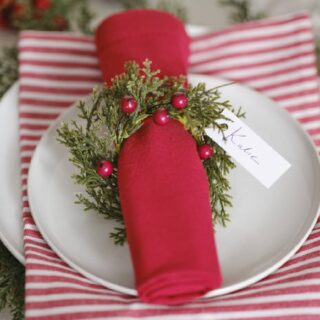 Rood servet met een kerstkrans met rode besjes eromheen