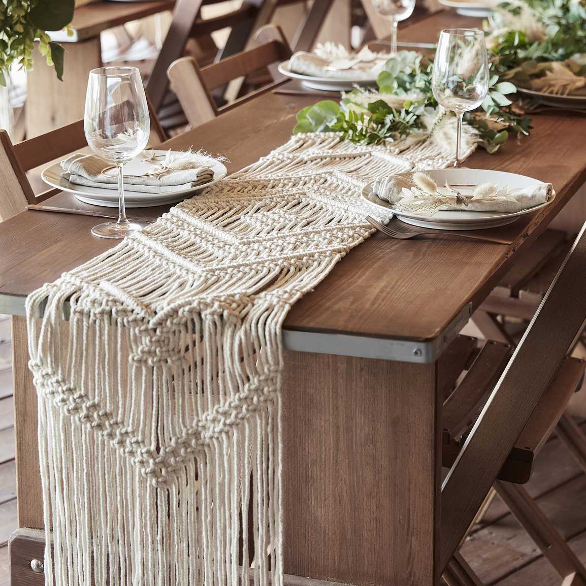 Houten tafel met borden glazen en een macrame tafelloper