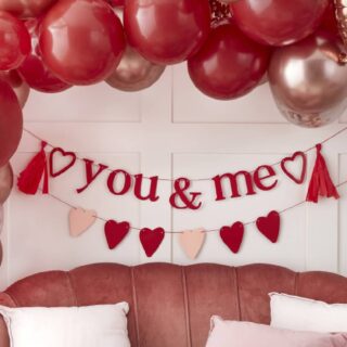 Slinger met hartjes en slinger met de tekst you & me hangen boven een roze bank