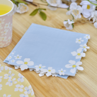 Pastelblauwe servetten met een bloemenrand van madeliefjes op een houten tafel