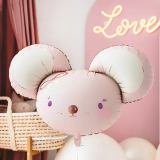 Folieballon van een lichtroze muisje met rose gouden details zweeft in een roze meisjeskamer met een rieten babymandje