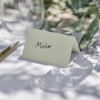 Saliegroen tafelkaartje staat op een witte dinertafel
