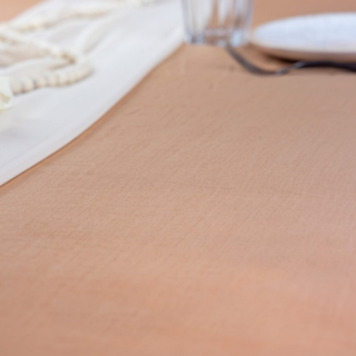 Rose drapeerdoek gemaakt van chiffon ligt op een tafel onder een wit doek, een houten kralenketting en een wit bord met glas