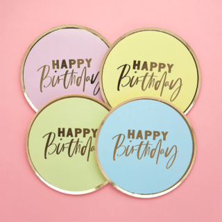 Bordjes in pasteltinten roze, geel, groen en blauw met een gouden rand en tekst happy birthday op een lichtroze achtergrond