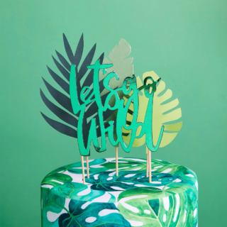 cocktailprikkers met jungle bladeren en de tekst lets go wild in het groen zitten in een taart voor een groene muur