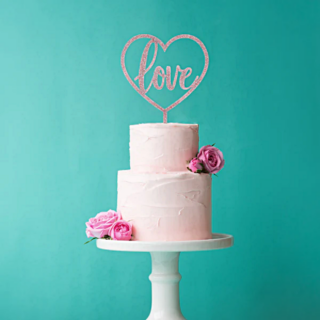 roze taart topper met de tekst love zit in een roze taart voor een blauwe muur