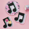 papieren servet in de vom van een zwarte muzieknoot met mintgroene, paarse en pastelroze strepen liggen op een roze achtergrond en zijn bedekt met cupcakes