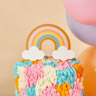 Regenboog taart topper zit in een regenboog taart en staat voor gele smileyballonnen en een perzikkleurige muur