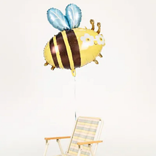 folieballon in de vorm van een hommel met een zonnebrilletje op zweeft boven een gele tuinstoel