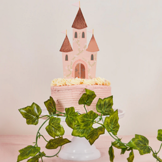 Roze taart op een wit plateau versierd met een kasteel in het rose en rosé goud met bloemen en eucalyptus