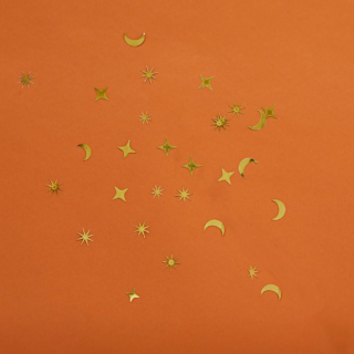 Gouden confetti in de vorm van sterren en een halve maan ligt op een oranje achtergrond