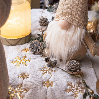 Tafelloper met gouden print versierd met een kerstmannetje en dennenappels met een laagje nepsneeuw erop