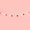 Slinger met roze, rode en witte hartjes hangt voor een roze muur