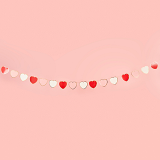 Slinger met roze, rode en witte hartjes hangt voor een roze muur