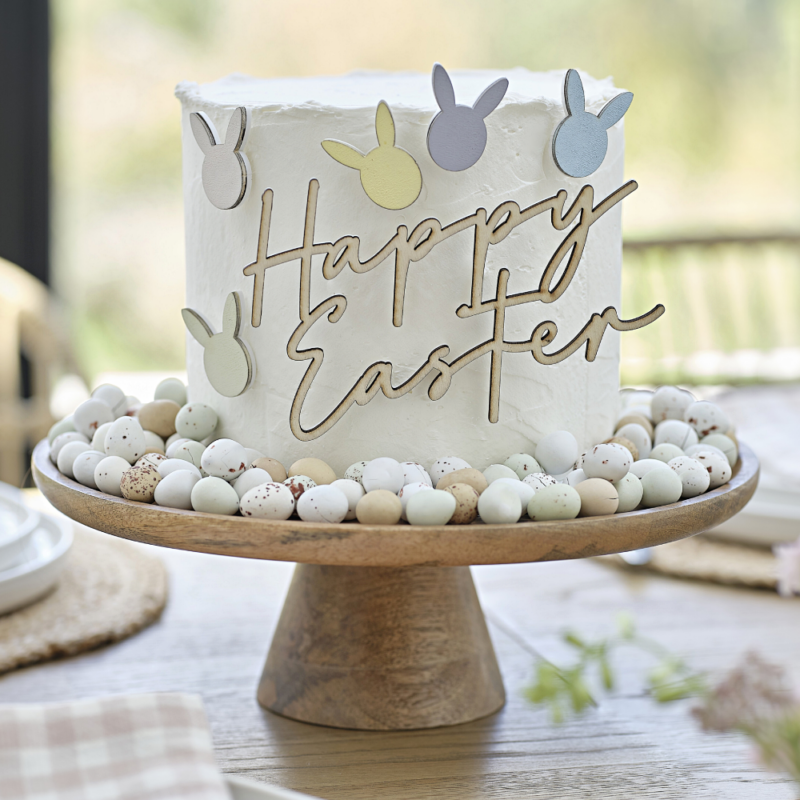 Houten taart toppers met konijntjes en de test happy easter zitten in een witte taart op een houten plateau