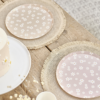 Roze en beige bordjes met madeliefjes staan op rieten placemats