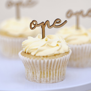 Houten cupcake toppers met de tekst one zitten in een creme cupcake