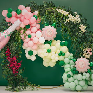 lichtroze en creme ballonnenboog met bloemen en groene bladeren