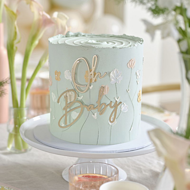 Metalen taart topper met de tekst oh baby zit in een salie groene taart met bloemen versiering