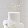 Gouden cake topper van acryl met de tekst mr and mrs zit in een witte taart met bloemen