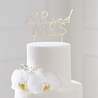 Gouden cake topper van acryl met de tekst mr and mrs zit in een witte taart met bloemen