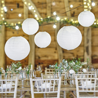 witte lampionnen hangen boven een rustiek versierde bruiloft tafel