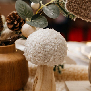 houten paddenstoel met witte teddy stof staat op een houten tafel versierd met kerst decoratie