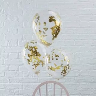 Drie confetti ballonnen gevuld met gouden confetti bevestigd aan een stoel