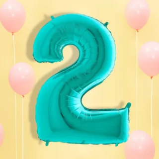 Turquoise folieballon op een lichtgele achtergrond met pastelroze ballonnen en wit lint
