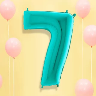 Turquoise folieballon op een lichtgele achtergrond met pastelroze ballonnen en wit lint