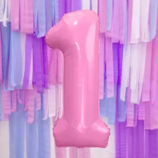 Roze folieballon in de vorm van cijfer 1 met op de achtergrond roze en paarse crepe slingers
