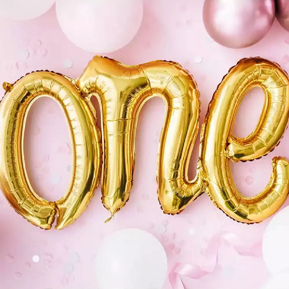 Folieballon in de vorm van het woord One op roze confetti en roze ballonnen