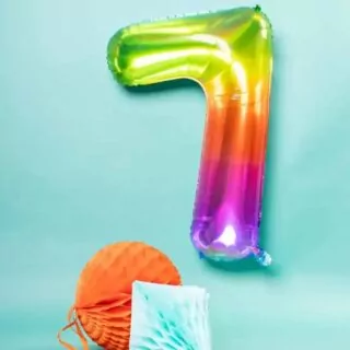 Regenboogkleurige folieballon cijfer 7 op een blauwe achtergrond met een oranje en lichtblauwe honeycomb
