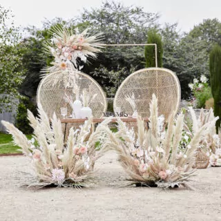 Twee rotan stoelen die buiten staan omringd door pampagras