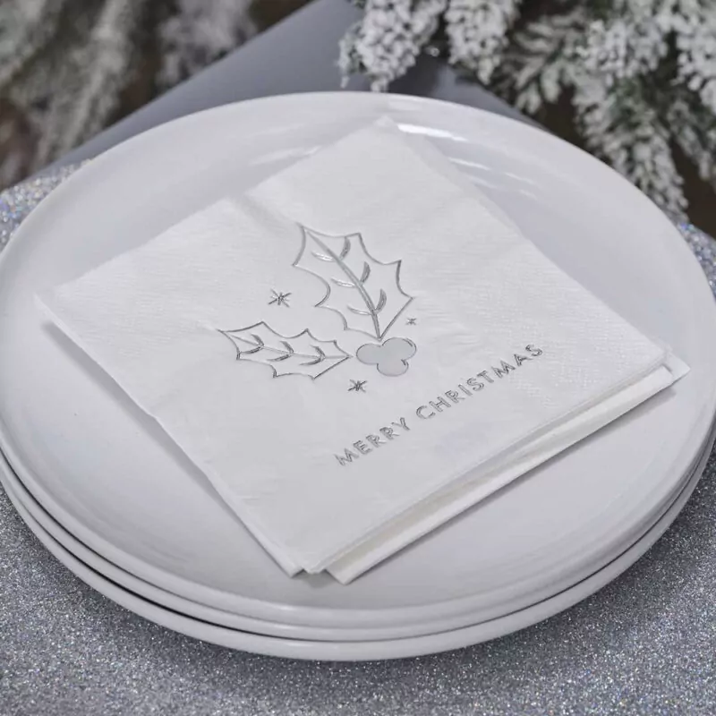 Stapeltje witte borden met daarop een stapeltje witte kerstservetten