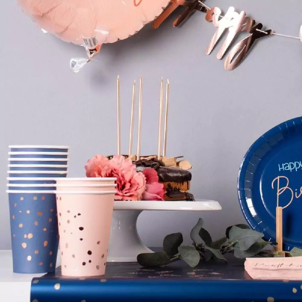 Versierde tafel met roze en blauwe bekers, roze servetten en bloemen
