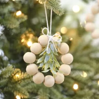 Kerstboom met daarin een hanger met houten kralen en een takje