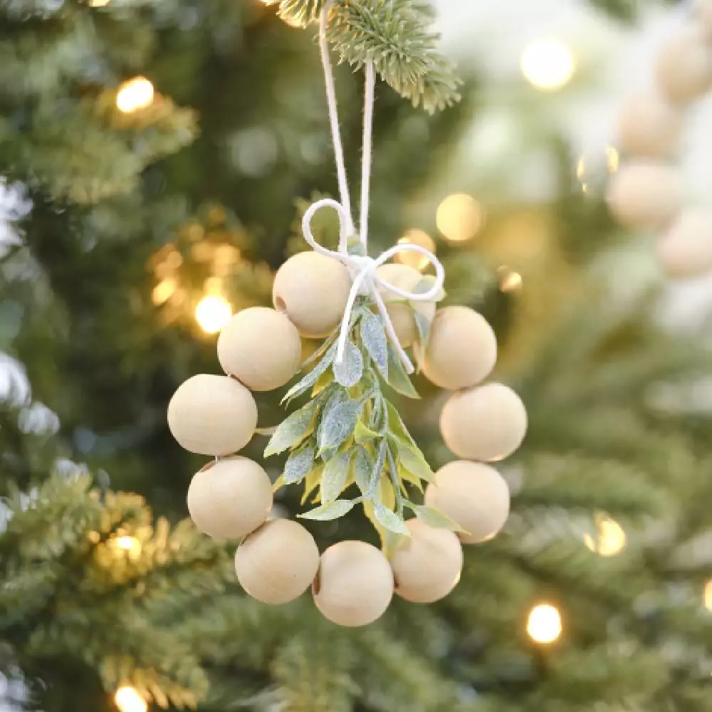 Kerstboom met daarin een hanger met houten kralen en een takje