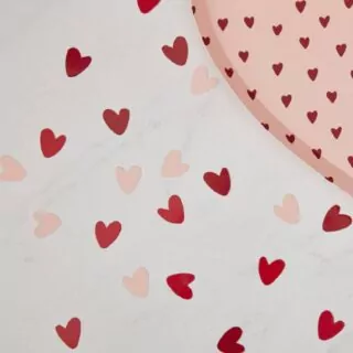Confetti hartjes op tafel in de kleuren donkerrood, rood en lichtroze