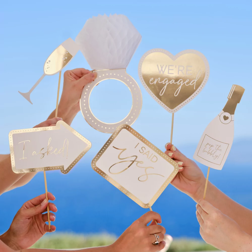 Gouden en witte photobooth props in de vorm van een ring, hartjes, een champagnefles en een champagneglas