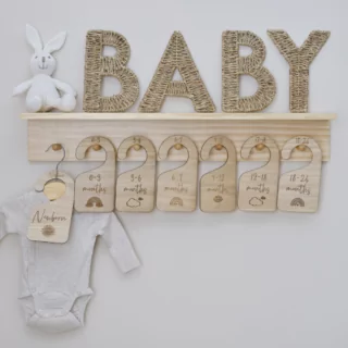 Houten plank met houten hangers eraan en een wit rompertje